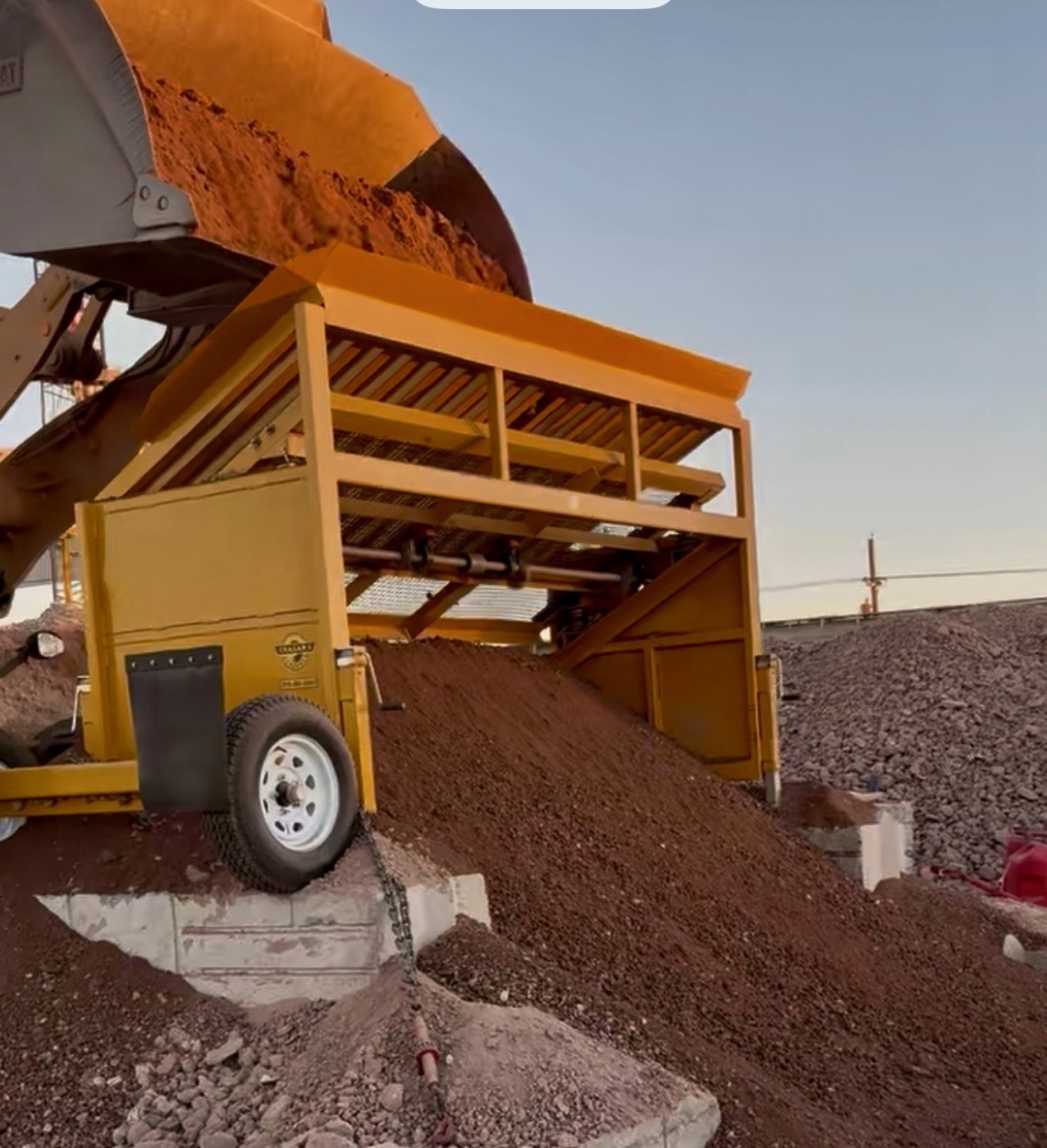Ceasars 10S screening aggregate with a fresh gravel pile at dusk